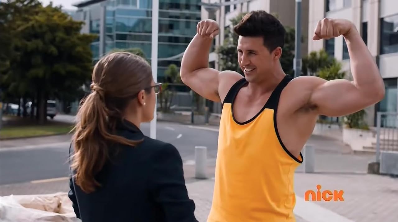 Sam Barton as Bodybuilder in Power Rangers Dino Charge, flexing his arms in a yellow vest opposite Claire Blackwelder.